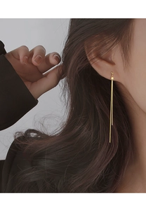 Detail of long gold tassel earrings on model showing elegant minimalist drapes