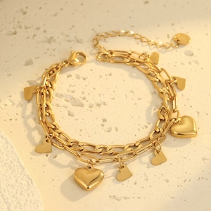 Pulsera vintage de doble capa dorada con colgantes de corazón sobre una piedra con textura