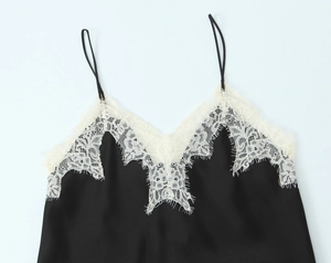 Detail of black satin camisole featuring delicate white eyelash lace trim and thin straps
