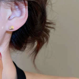 Close-up of minimalist golden cube stud earrings worn by a model for a daily look