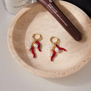Orecchini a cerchio dorati con peperoncino rosso e perle su vassoio di pietra