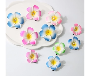 Flat lay detail of pastel frangipani hair clips with pearls on a white cloud tray
