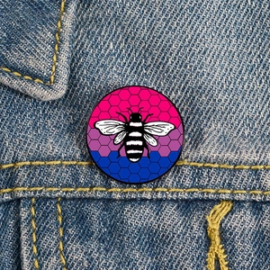 Primer plano de un pin de abeja arcoíris en una chaqueta vaquera con patrón de panal