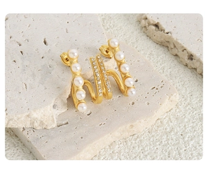 Detail of gold double-layer titanium earrings with white pearls and sparkling zircons
