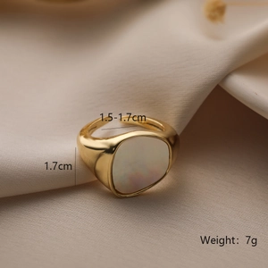 Detail of gold-plated ring with white shell inlay on champagne silk background