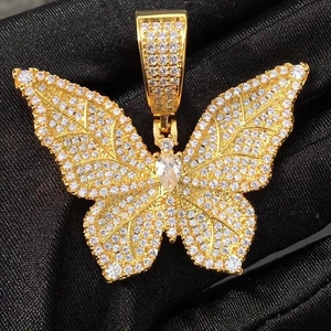 Macro shot of gold butterfly pendant with sparkling crystals on black silk background