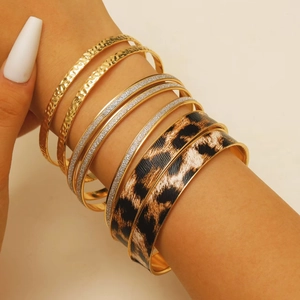 Detail view of 8-piece stacked bracelets featuring leopard print, glitter, and gold hammer texture
