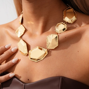 Close-up of golden geometric faceted metal link necklace with high polish finish