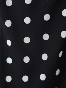 Detailed close-up of classic black and white polka dot fabric with ruffle hem design