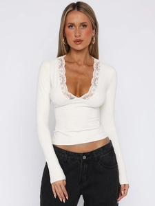 Detail shot of the deep V-neckline featuring delicate white floral lace trim on long sleeve top