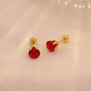 Détail de boucles d'oreilles en zircon rouge doré avec fermoir à vis sécurisé