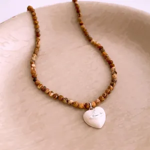 Vintage stone bead necklace with a white heart charm featuring a Saturn ring pendant