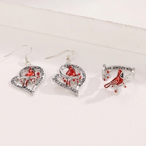 Detail view of heart-shaped earrings and cardinal ring set in polished silver and red enamel