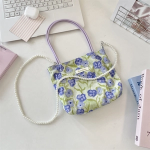 Detail of floral canvas tote bag featuring purple cord handles and pearl bead strap