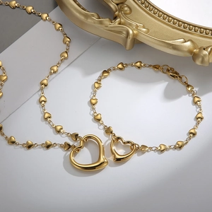 Close-up of golden heart jewelry set with open heart pendant and solid heart links