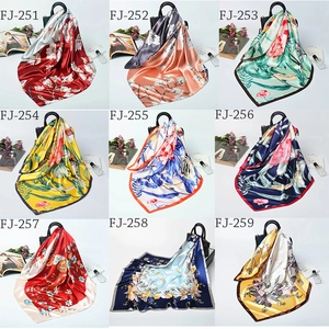 Collection of nine colorful floral satin scarves styled on handbags with fashion props