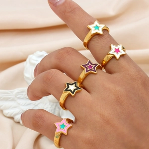 Set of five gold star rings with colorful enamel inlay on an elegant hand model