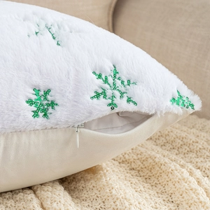 Detail of white plush pillow cover featuring green sequined snowflake and hidden zipper