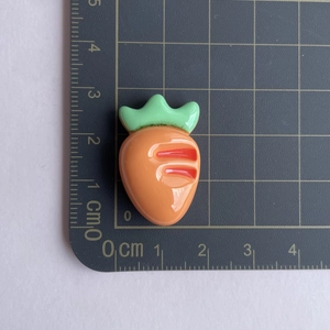 Detailed view of glossy resin carrot charm showing dimensions on a scale mat