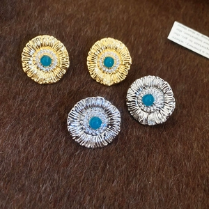 Detail of sunflower stud earrings in gold and silver with blue stones and zircons