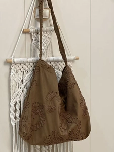 Detail of brown faux suede tote with intricate floral embroidery and wide shoulder strap