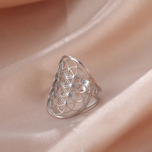 Macro shot of silver hollow geometric flower pattern ring on soft satin background