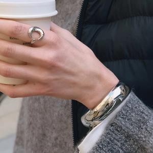 Detail shot of minimalist silver polished metal ring and wide bangle on wrist