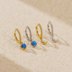 Macro shot of S925 silver opal earrings in gold and silver finishes on stone