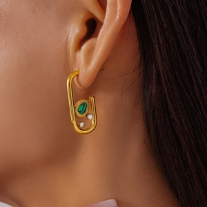 Macro detail of U-shaped gold earrings featuring malachite, white pearl and zircon accents