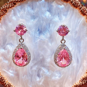 Detailed close-up of pink pear-cut drop earrings with sparkling halo zircon setting
