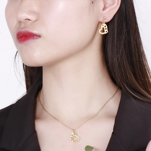 Close-up of golden hollow heart necklace and earrings set worn by a female model