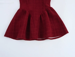 Détail de la texture en tweed rouge et de l'ourlet plissé de cette robe courte élégante