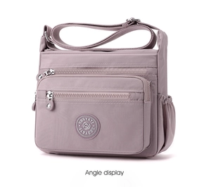 Detailed side view of pink nylon crossbody bag with zipper pockets and wide shoulder strap
