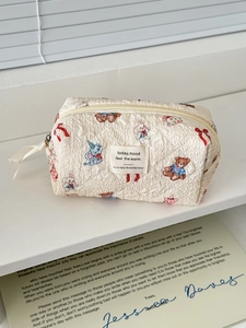 Close-up of quilted fabric makeup bag with cute cartoon animal prints and metal zipper