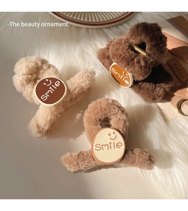 Detailed view of three plush hair claws in cream and brown with smile patches