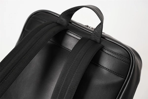 Detail view of reinforced top handle and woven shoulder straps on black leather backpack