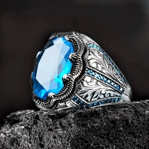 Anello vintage in argento con gemma blu ovale e incisioni floreali su roccia nera