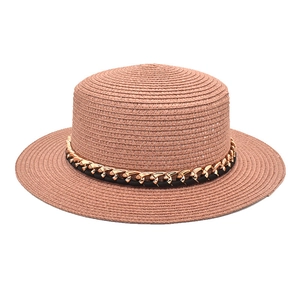 Détail d'un chapeau canotier rose avec bande en cuir noir et chaîne dorée décorative