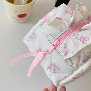 Detail of floral ribbon cosmetic bag featuring pink zipper and quilted fabric texture