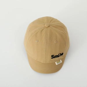Makro-Detail einer khakifarbenen Baseballkappe mit Smile-Stickerei und feiner Twill-Struktur