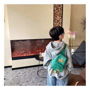 Dettaglio della borsa a tracolla a forma di papera verde indossata da un bambino