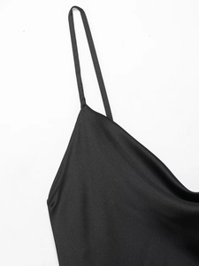 Detailed close-up of smooth black satin fabric and delicate spaghetti straps of the dress