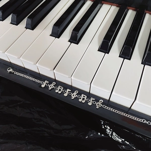 Artistic silver musical note bracelet displayed on black and white piano keys