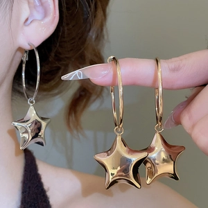 Macro di orecchini a cerchio con ciondolo a stella in oro e argento su una modella