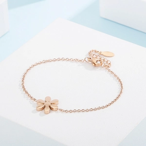 Detailed close-up of a rose gold floral bracelet with a matte flower charm and fine chain