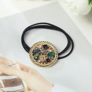 Détail d'un élastique baroque avec cristaux colorés et monture en métal doré sur noir