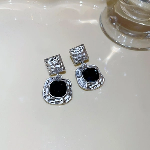 Macro shot of silver hammer texture and black square stone on vintage stud earrings