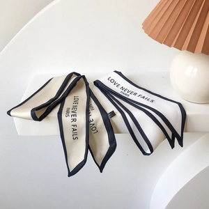 Detail of silk hair scarves with LOVE NEVER FAILS PARIS text on white steps
