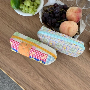 Astucci per penne floreali e patchwork su tavolo in legno con cesto di frutta