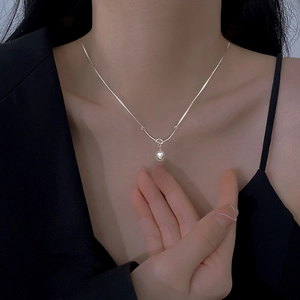 Elegant single pearl pendant necklace on a silver chain worn with a black blazer